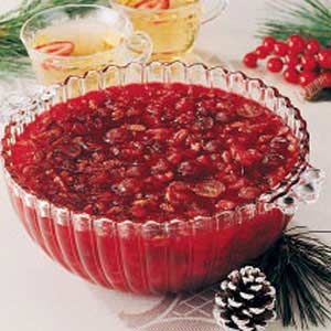 a bowl filled with cranberry sauce next to pine cones and other holiday decorations