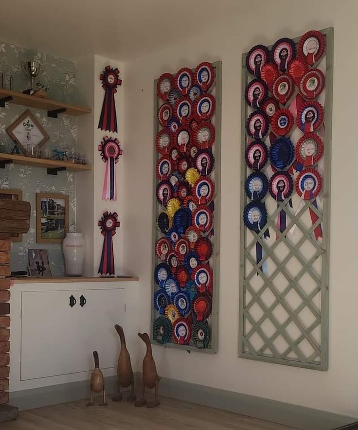 two wall hangings with ribbons on them in a living room next to a fireplace