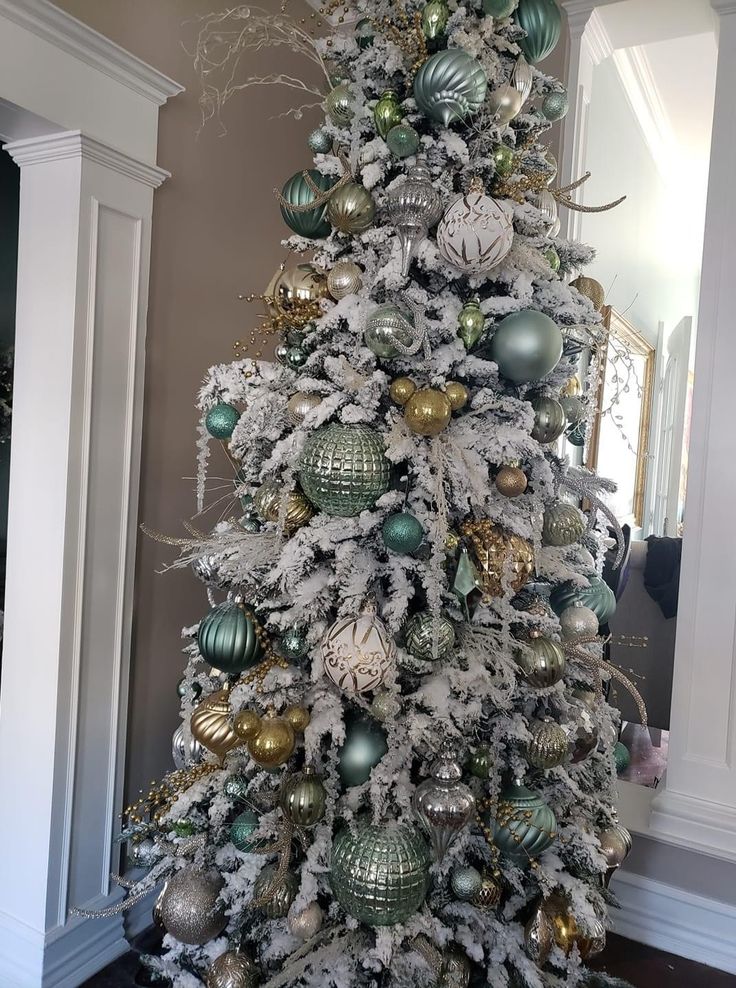 a white christmas tree with green and gold ornaments