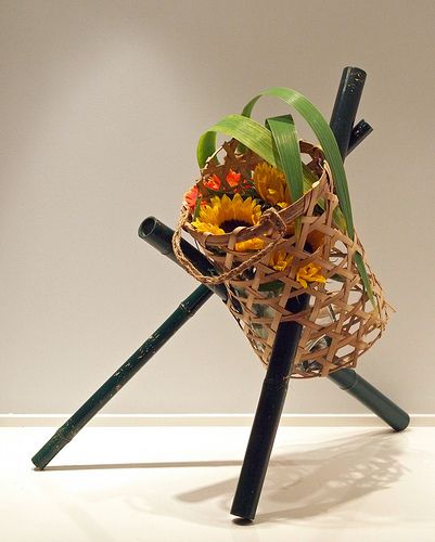 a basket with flowers in it sitting on a stand