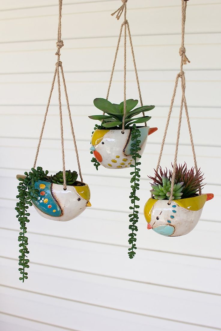 three hanging planters with succulents and plants in them on the side of a house