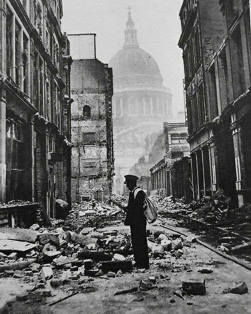 an old black and white photo of a person standing in the middle of a destroyed street