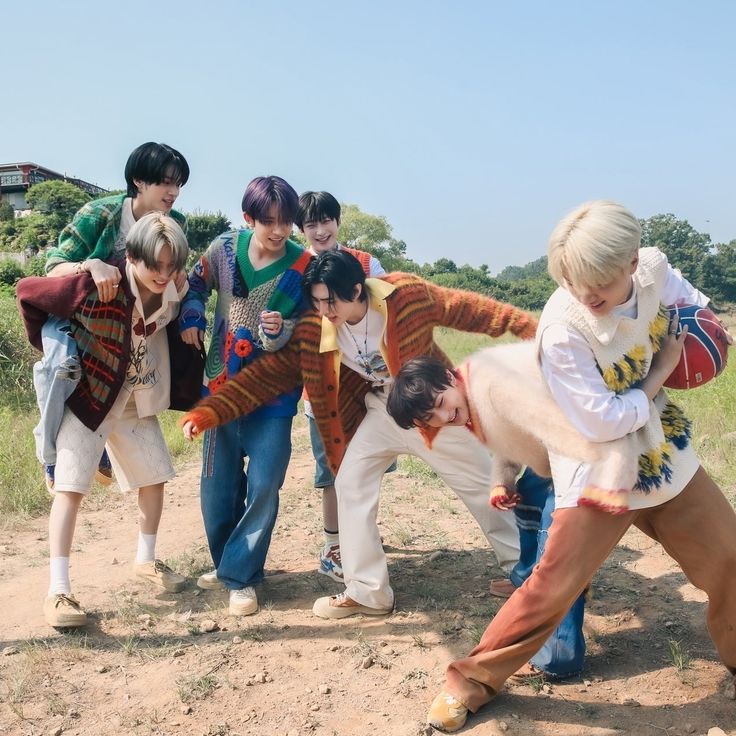 a group of young people standing on top of a dirt road next to each other