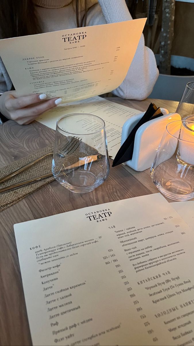 a person sitting at a table with some wine glasses and menus on the table