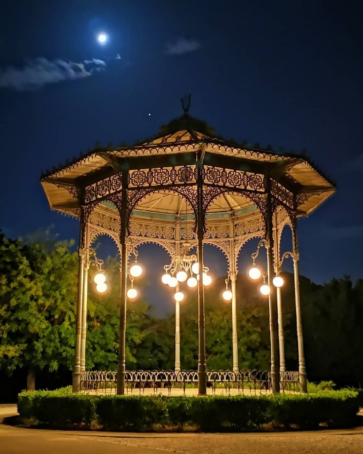 a lit up gazebo in the middle of a park at night