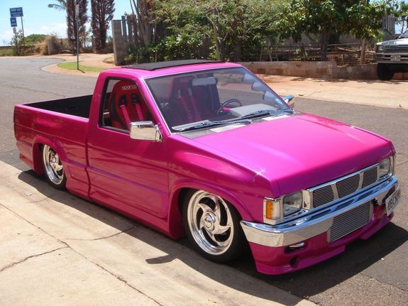 a pink pick up truck parked on the street