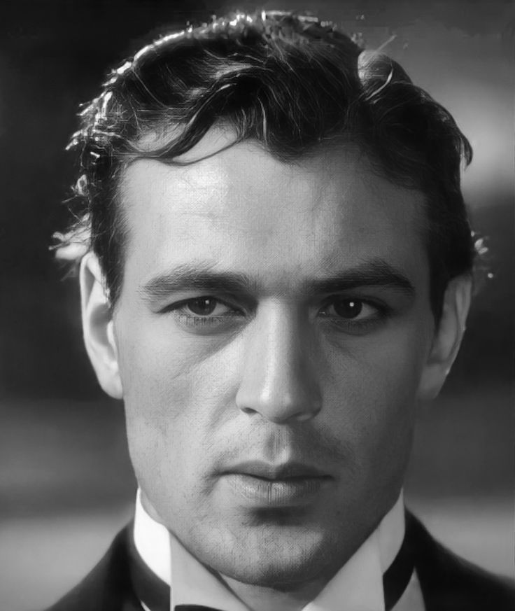 a black and white photo of a man in a tuxedo looking at the camera