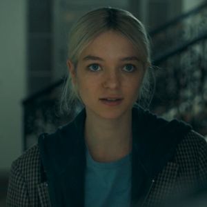 a woman with blonde hair and blue eyes looks at the camera while standing in front of stairs