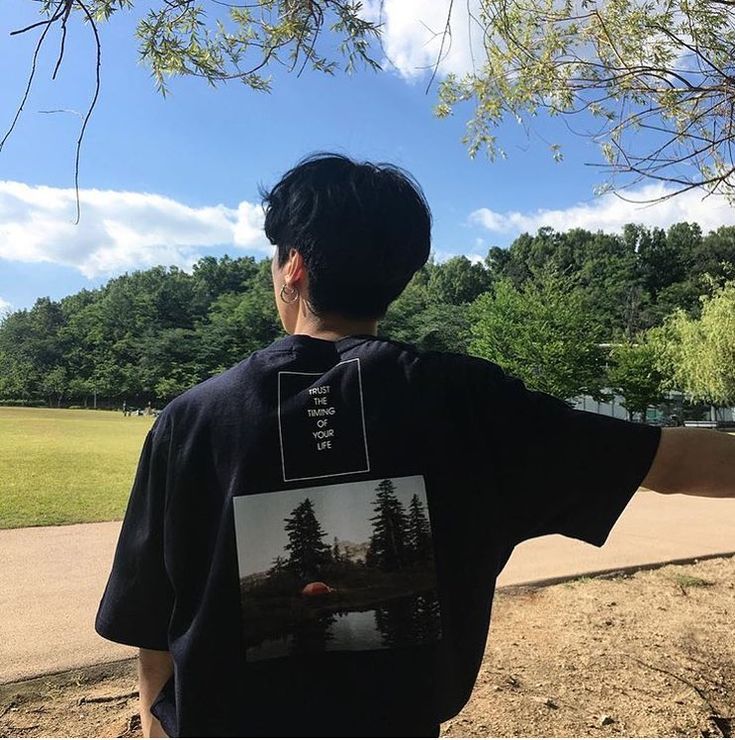 a young man standing next to a tree