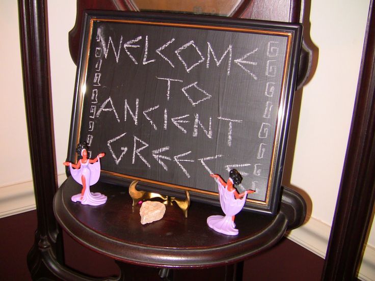 a welcome sign is placed on top of a small blackboard in front of a mirror