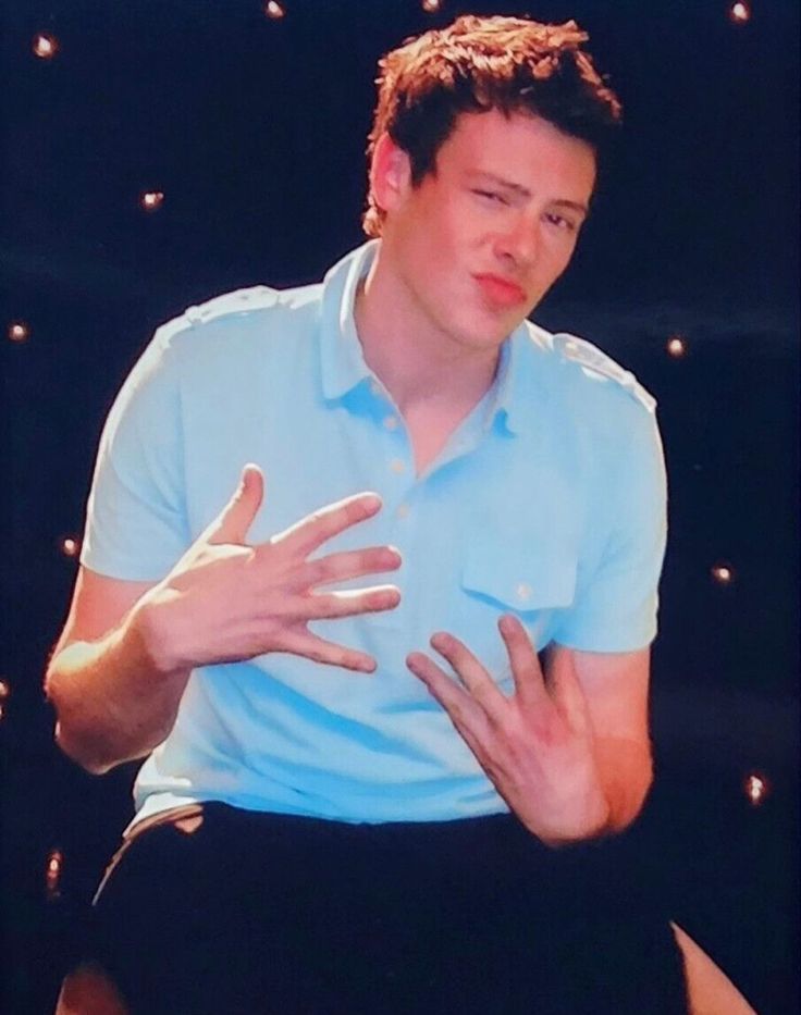 a man sitting in a chair holding his hands out to the side while wearing a blue shirt and black pants