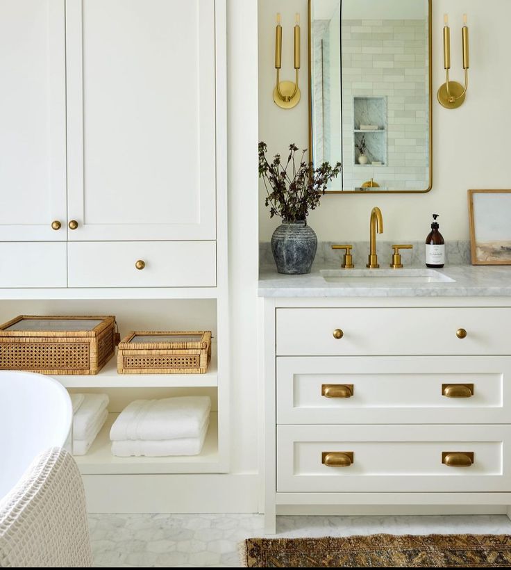 a bathroom with white cabinets and gold handles