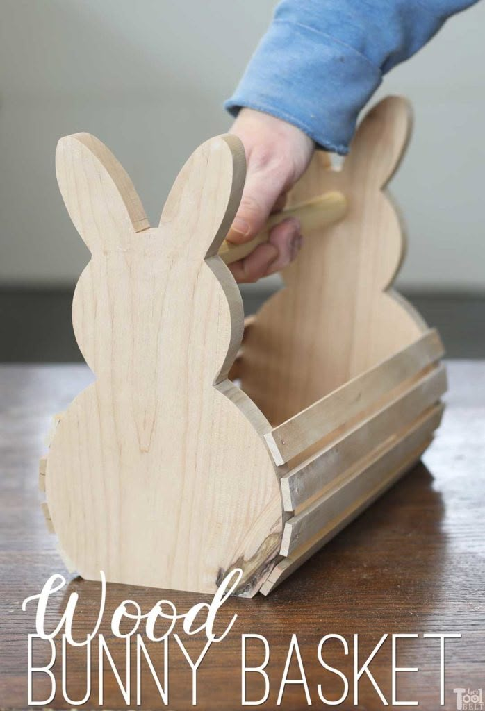 a wooden bunny basket sitting on top of a table next to a person's hand