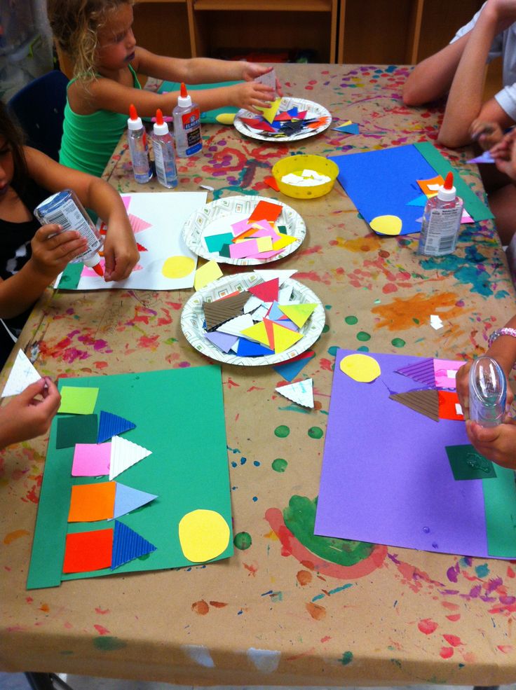 children are sitting at a table making crafts with paper plates and watercolors on them