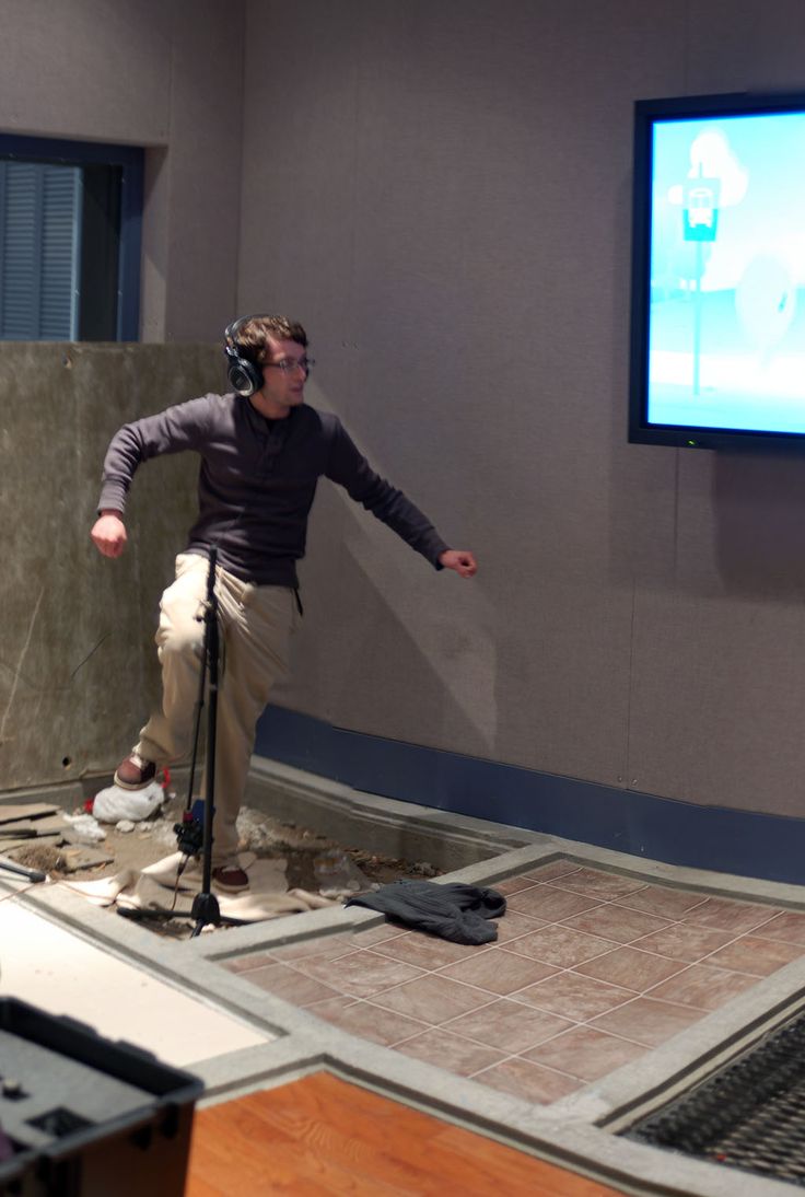 a man standing in front of a tv with headphones on while holding a microphone