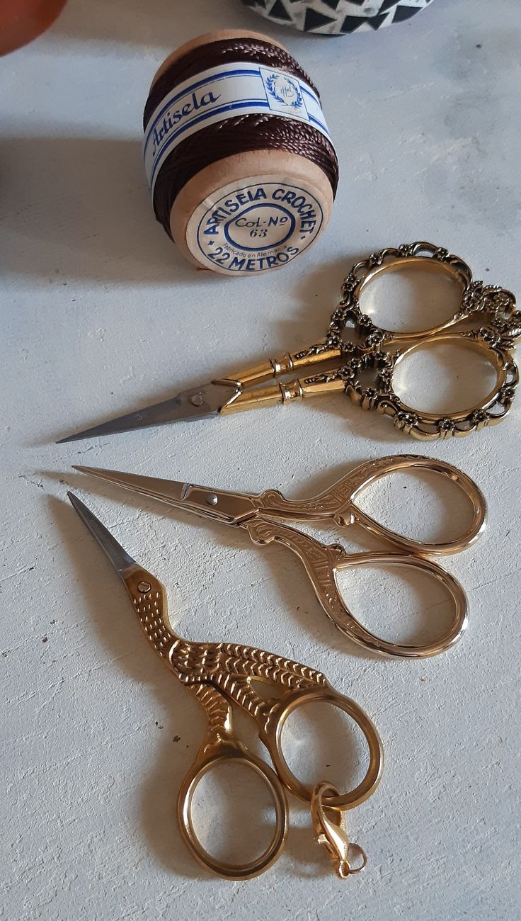 three pairs of scissors sitting on top of a table next to a spool of thread