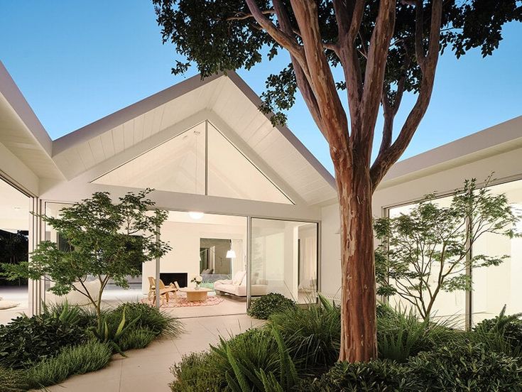 a house with a large tree in the front yard and patio area next to it