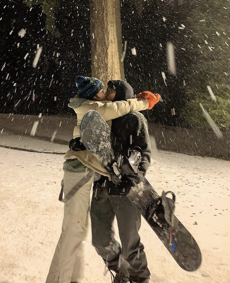 two snowboarders hugging each other in the snow