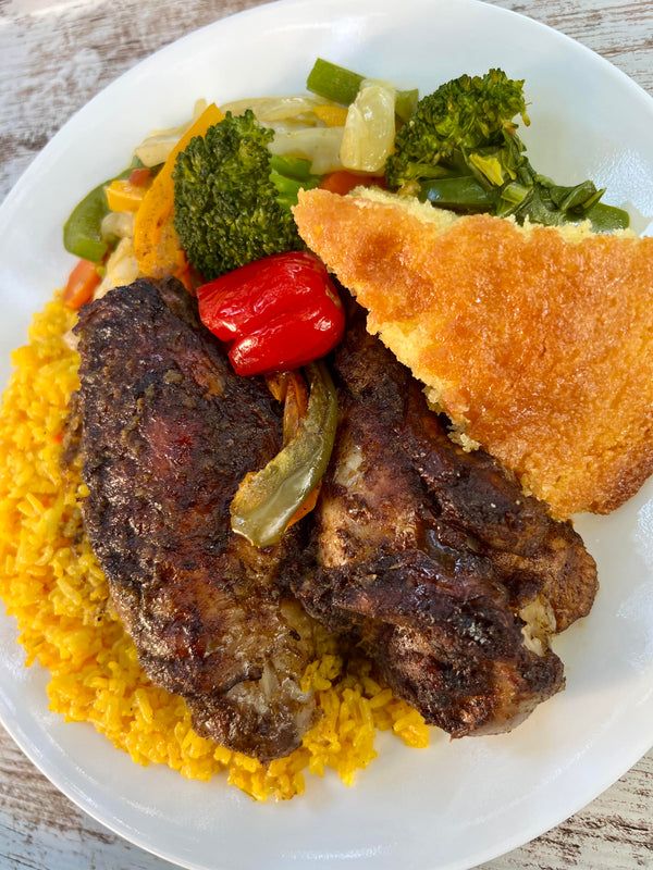 a white plate topped with meat, rice and veggies on top of a wooden table