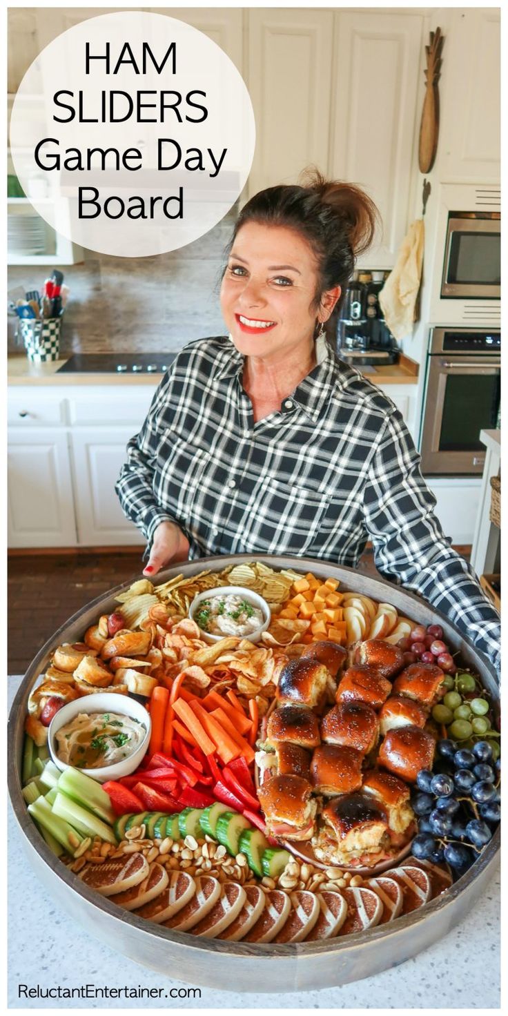 a woman standing in front of a platter full of food with the words ham sliders game day board