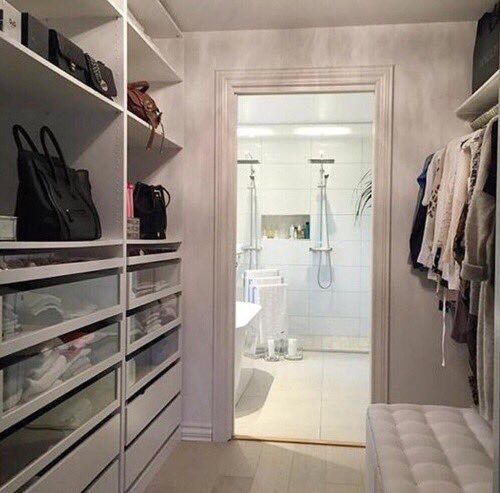 a walk in closet with white shelving and shelves filled with purses, shoes and handbags