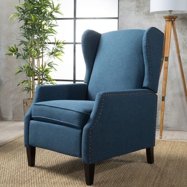 a blue chair sitting on top of a rug next to a lamp and potted plant