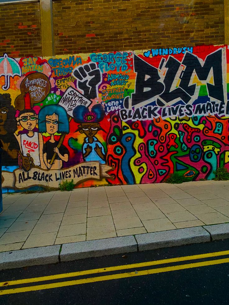 a wall covered in graffiti next to a street