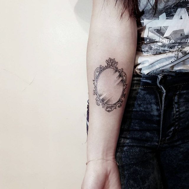 a woman's arm with a mirror tattoo on the left side of her arm