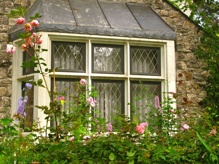 an old stone house with roses growing on the window sill