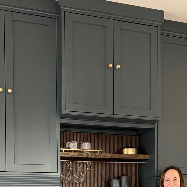 a woman is standing in the kitchen with gray cabinets