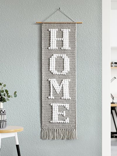 a wall hanging with the word home on it and a table in front of it