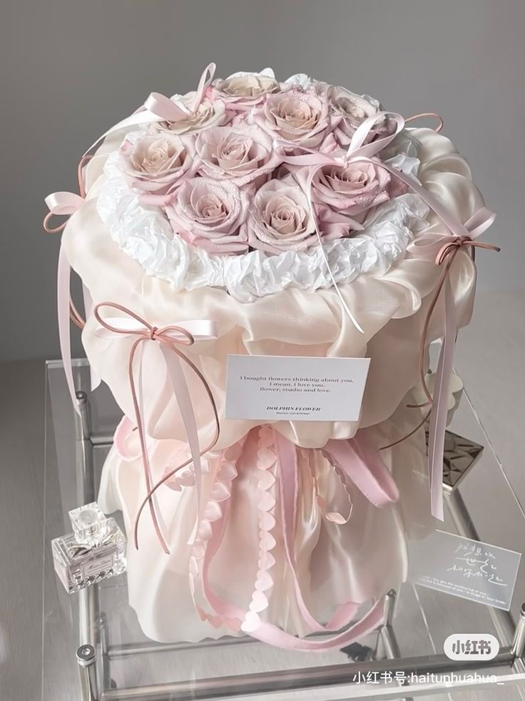 a large bouquet of pink roses in a clear box with ribbon around the top and bottom