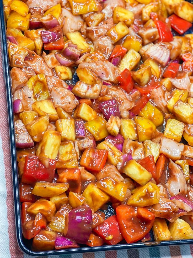 a pan filled with chicken and vegetables on top of a checkered table cloth,