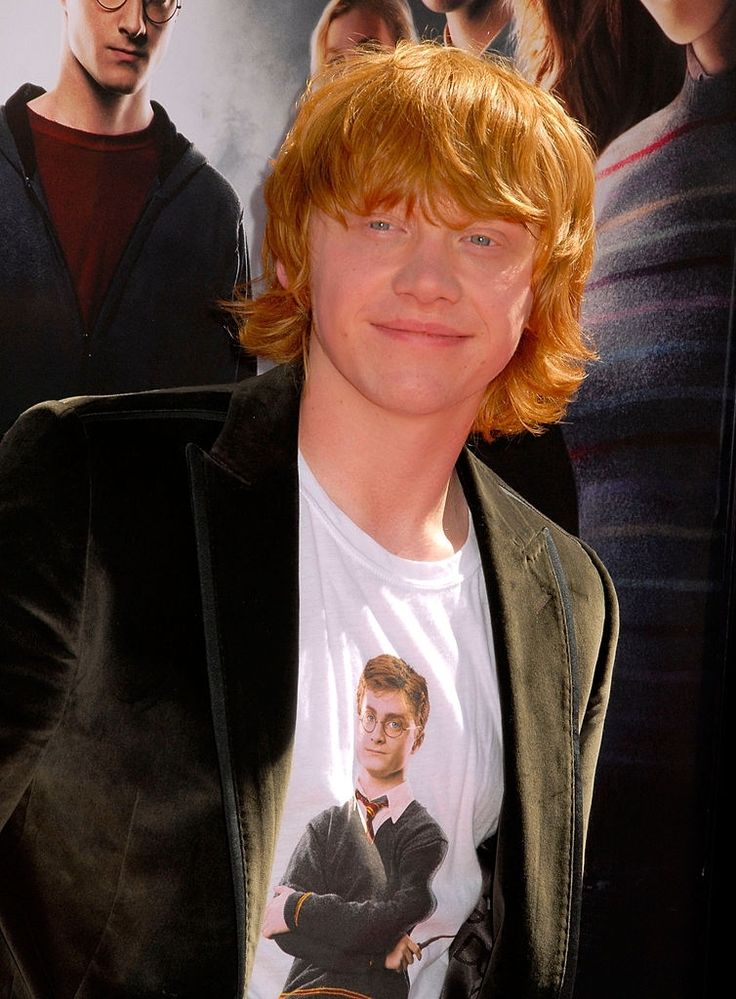 a young man with red hair and glasses posing for the camera in front of a harry potter poster