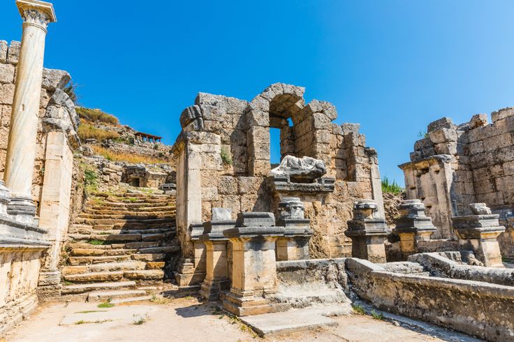 the ruins of an ancient roman city with stone columns and arches, against a blue sky