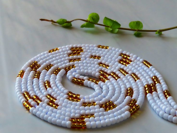 a white beaded necklace sitting on top of a table next to a twig