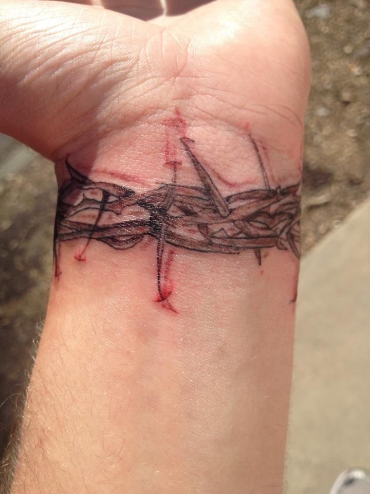 a person with a tattoo on their wrist that has a barbed wire design on it