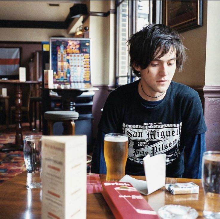 a man sitting at a table with two beers in front of him