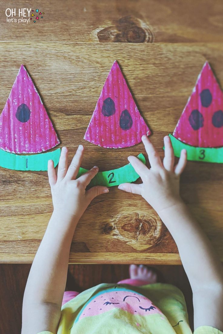 a child is playing with some paper watermelon shapes