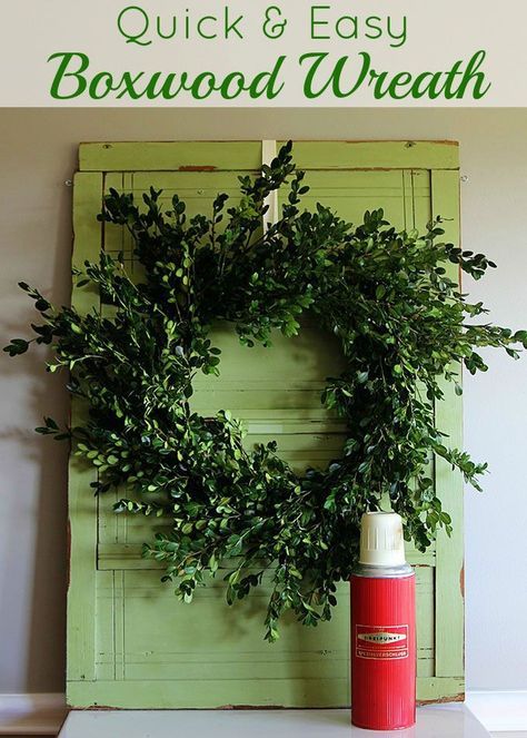 a green door with a wreath on it and a spray bottle sitting next to it