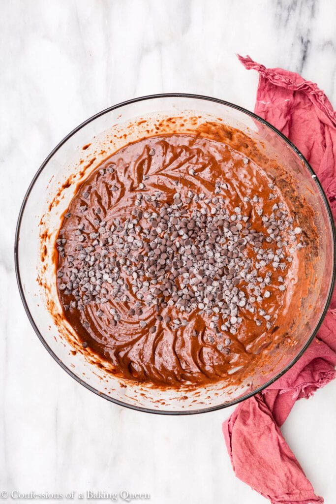 a glass bowl filled with brown sauce on top of a white marble counter next to a red napkin