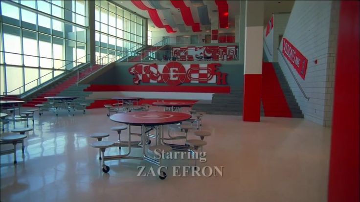 an empty cafeteria with red and white striped walls, tables and chairs on the floor