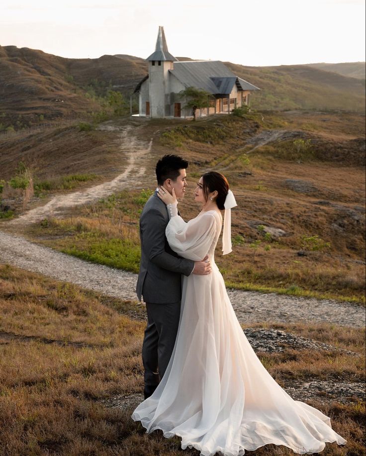 a bride and groom standing in front of a church on the side of a hill