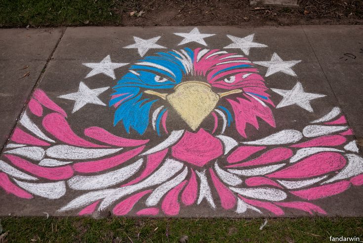 an eagle painted on the sidewalk with stars and stripes around its head in pink, blue, and white colors