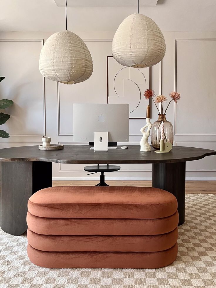 a desk with two lamps hanging above it and a laptop on the table in front of it