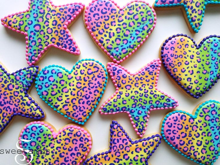 decorated cookies in the shape of hearts and stars on a white table with leopard print