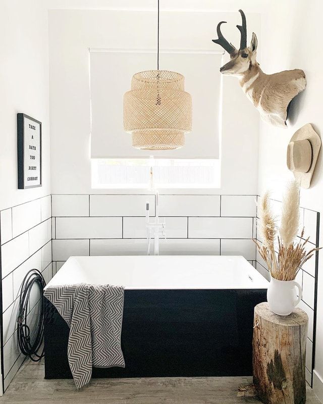 a white bath tub sitting under a window next to a deer head mounted on the wall