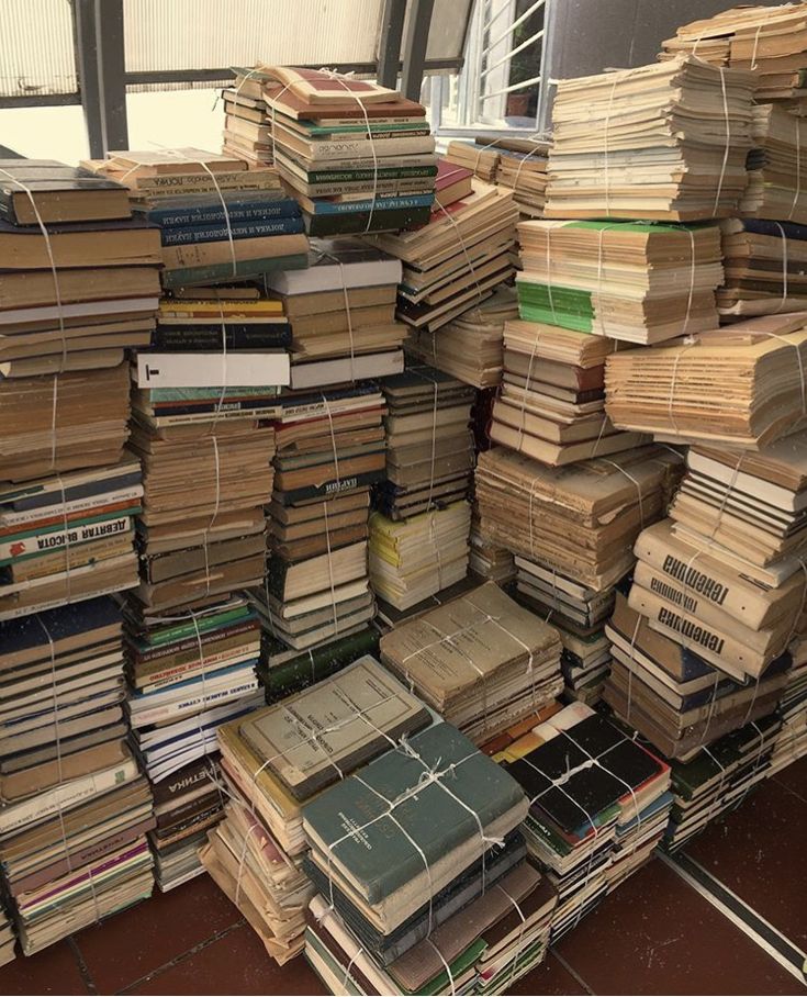 stacks of books are stacked on top of each other in the middle of a room