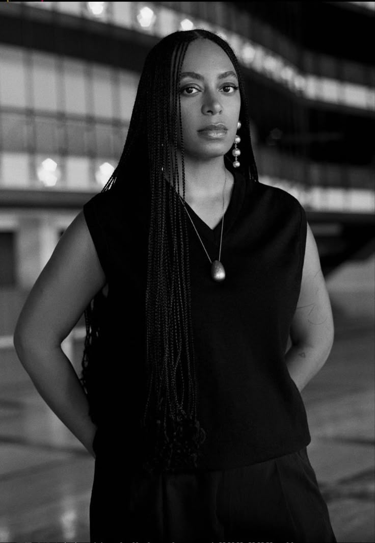 a black and white photo of a woman with her hands on her hips, looking at the camera