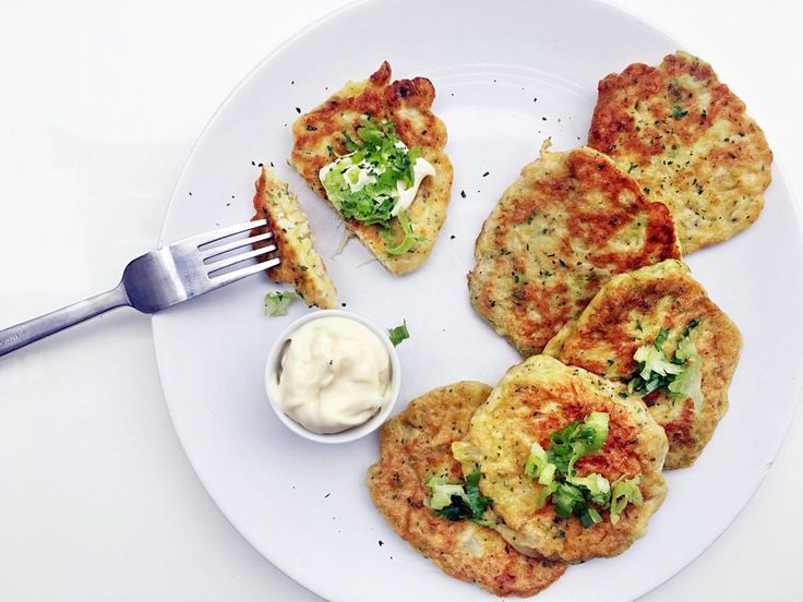 a white plate topped with crab cakes next to a small bowl of ranch dressing and a fork